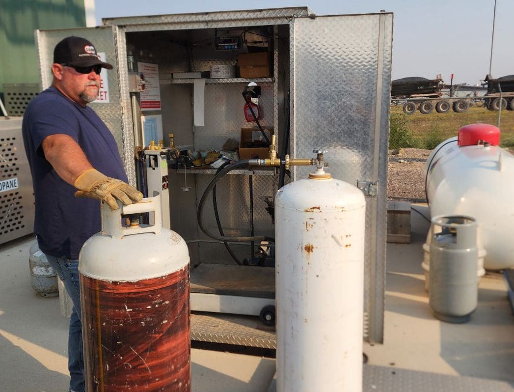 Patrons Coop Employee filling a propane bottle at the fill station